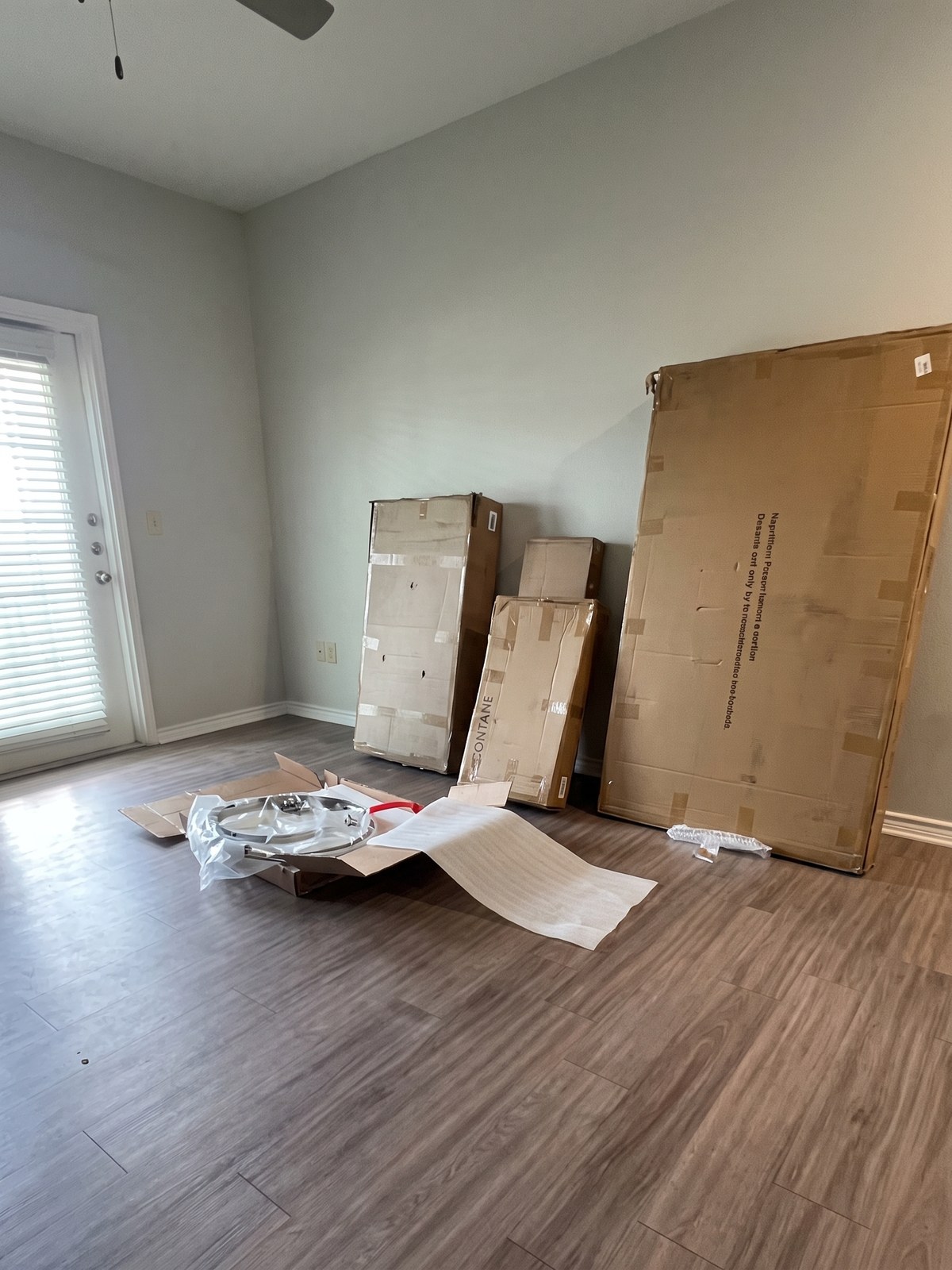 A dining room with flat-packed chair cartons and packaging spread across the floor before assembly.
