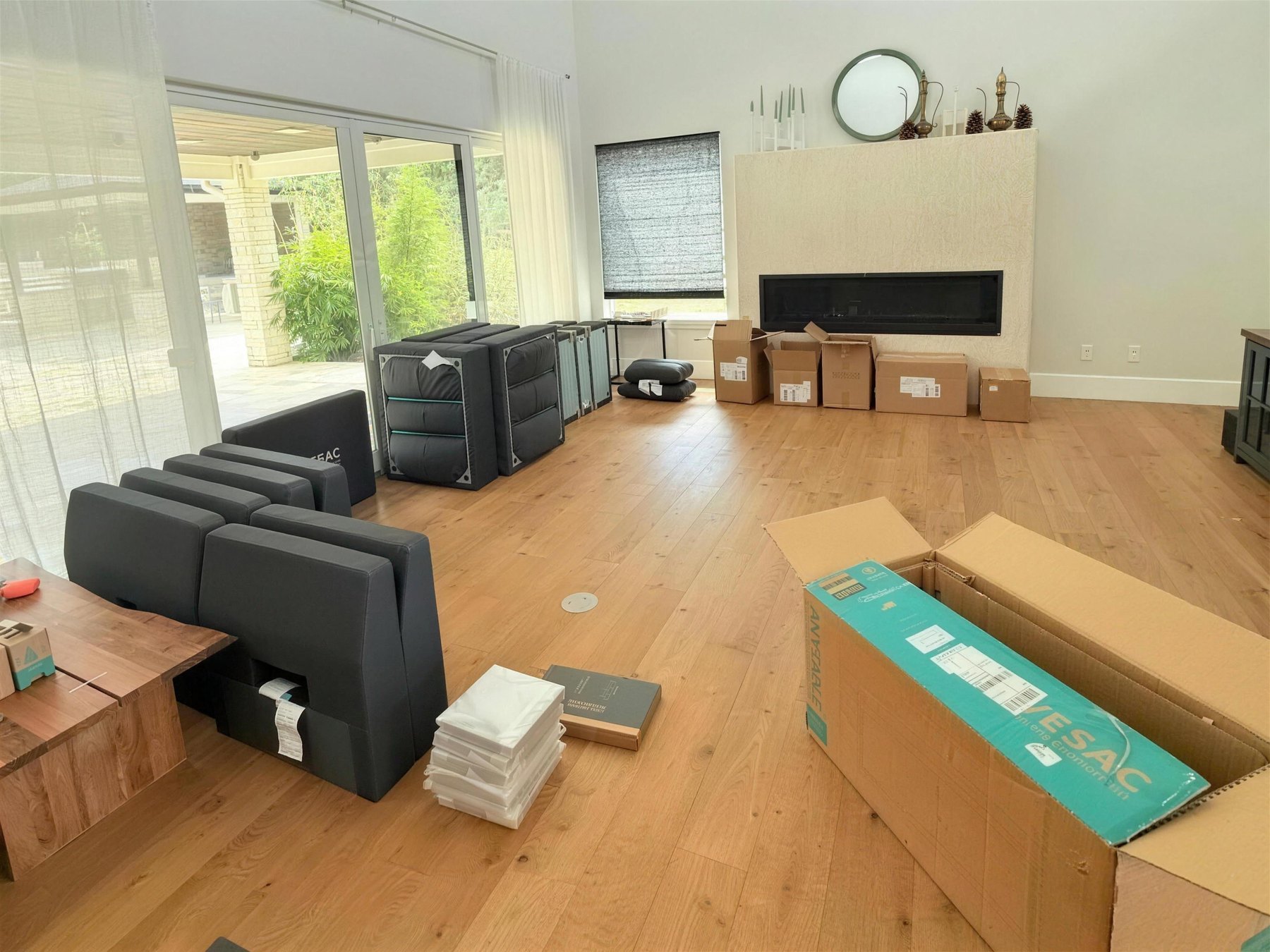 A double-height great room filled with flat cartons, foam inserts and loose upholstered panels across the floor.