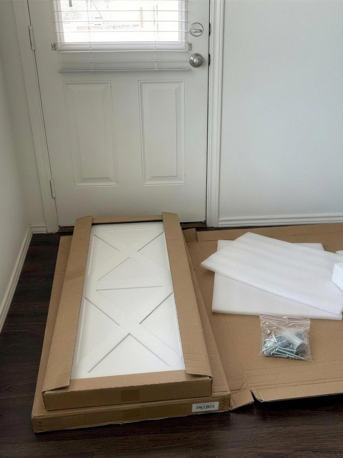 A hallway with flat cartons and packaging beside a part-built console.