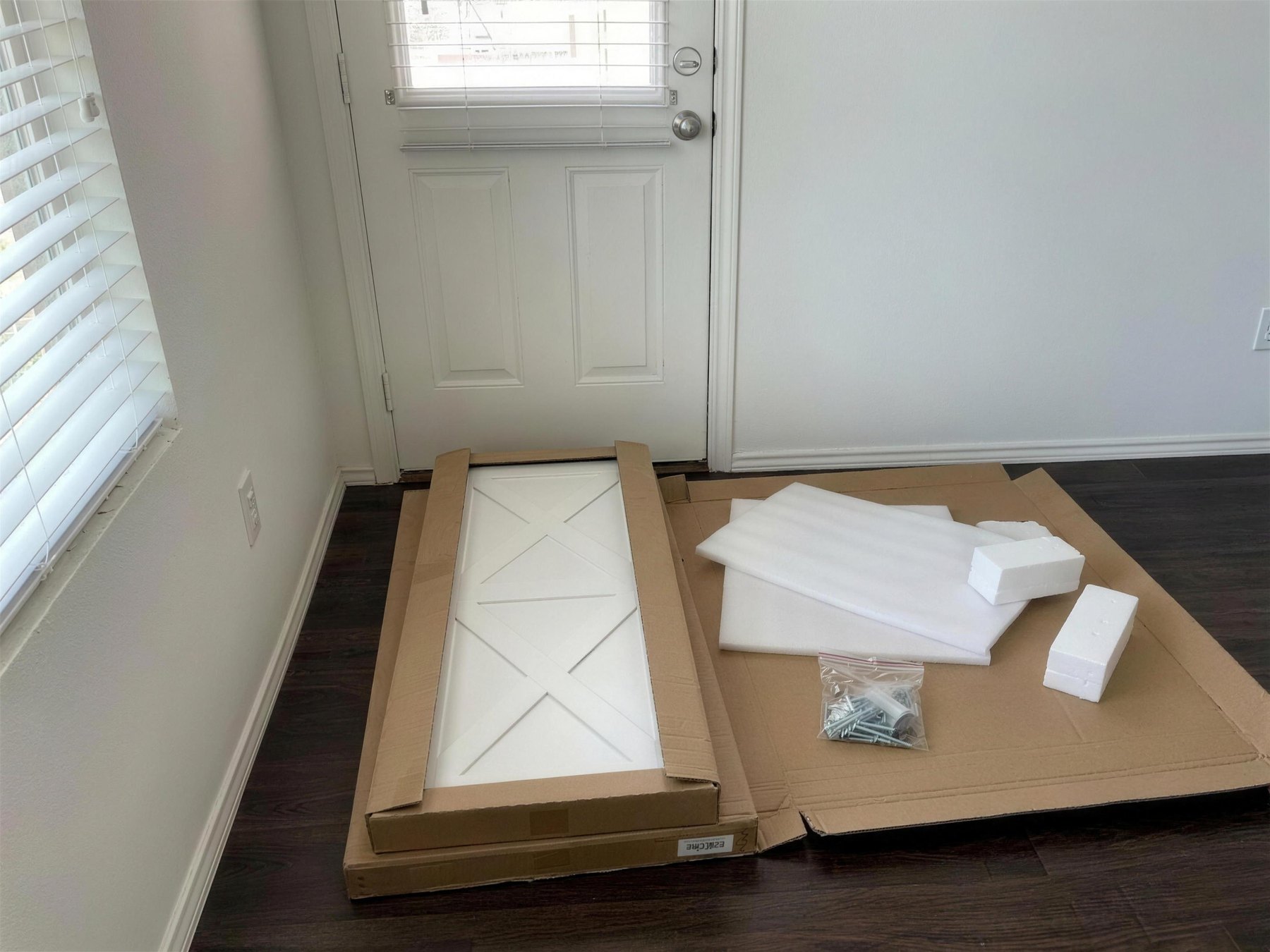 A hallway with flat cartons and packaging beside a part-built console.