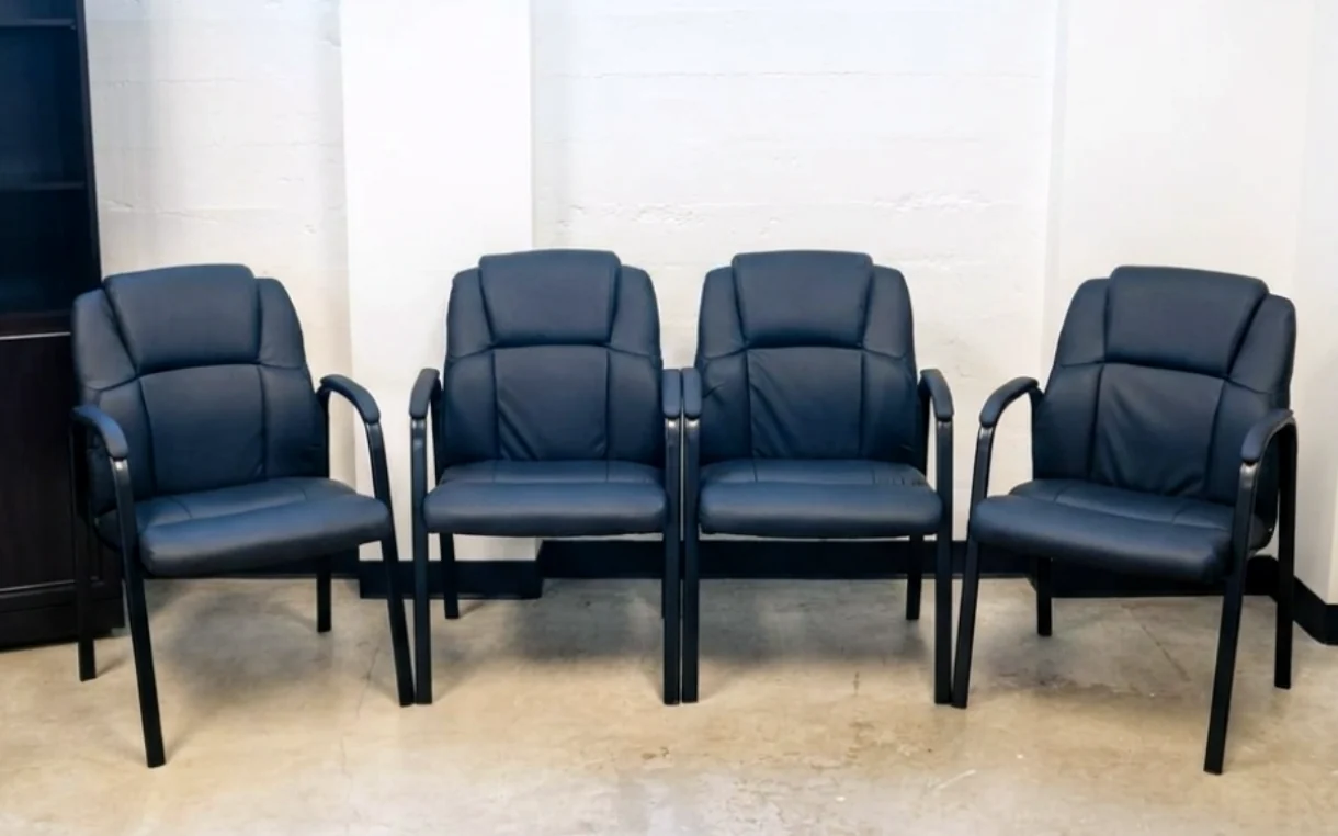 A row of task chairs assembled and lined up along an office wall.