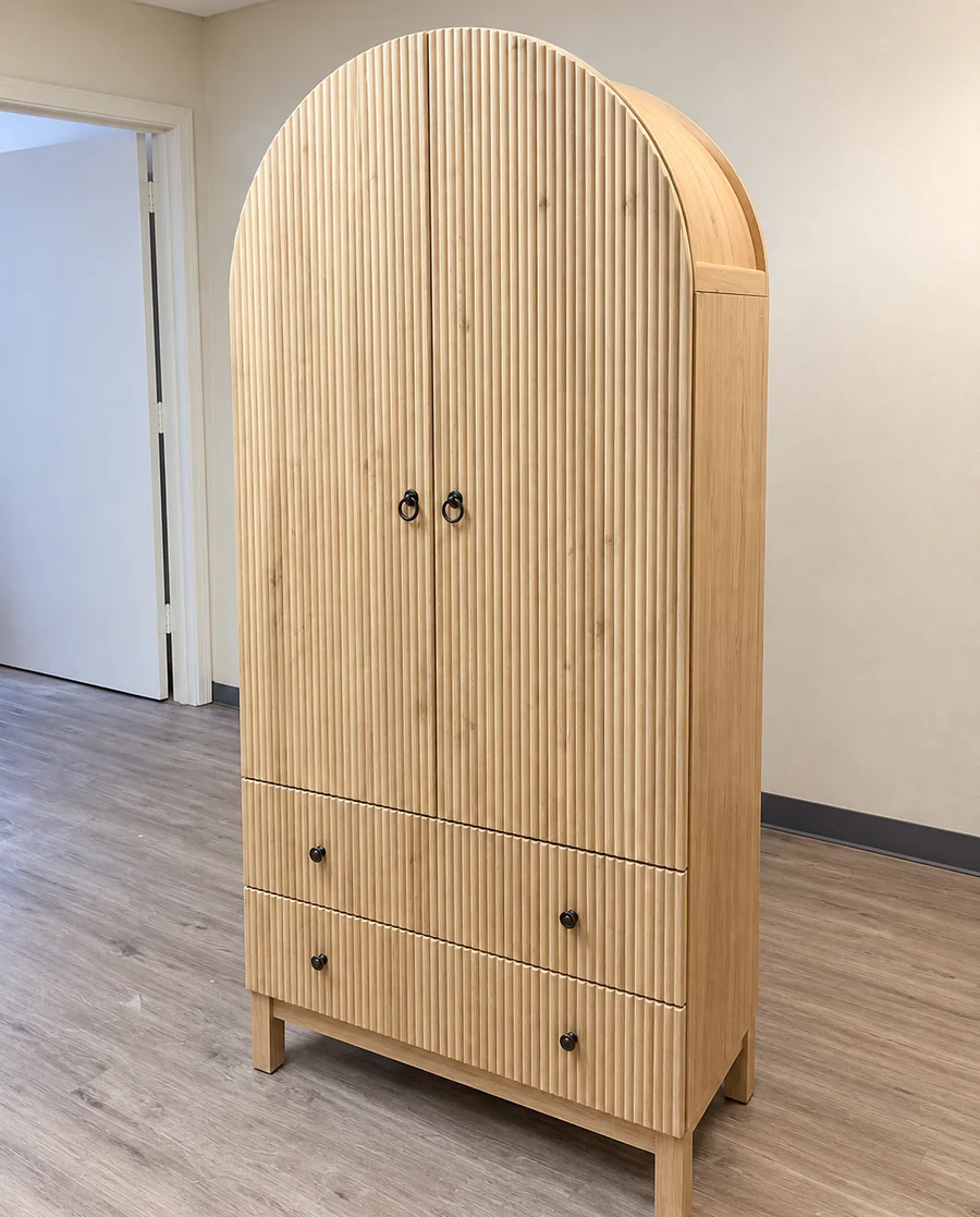 An arched oak wardrobe with drawers, assembled and set against a bedroom wall.
