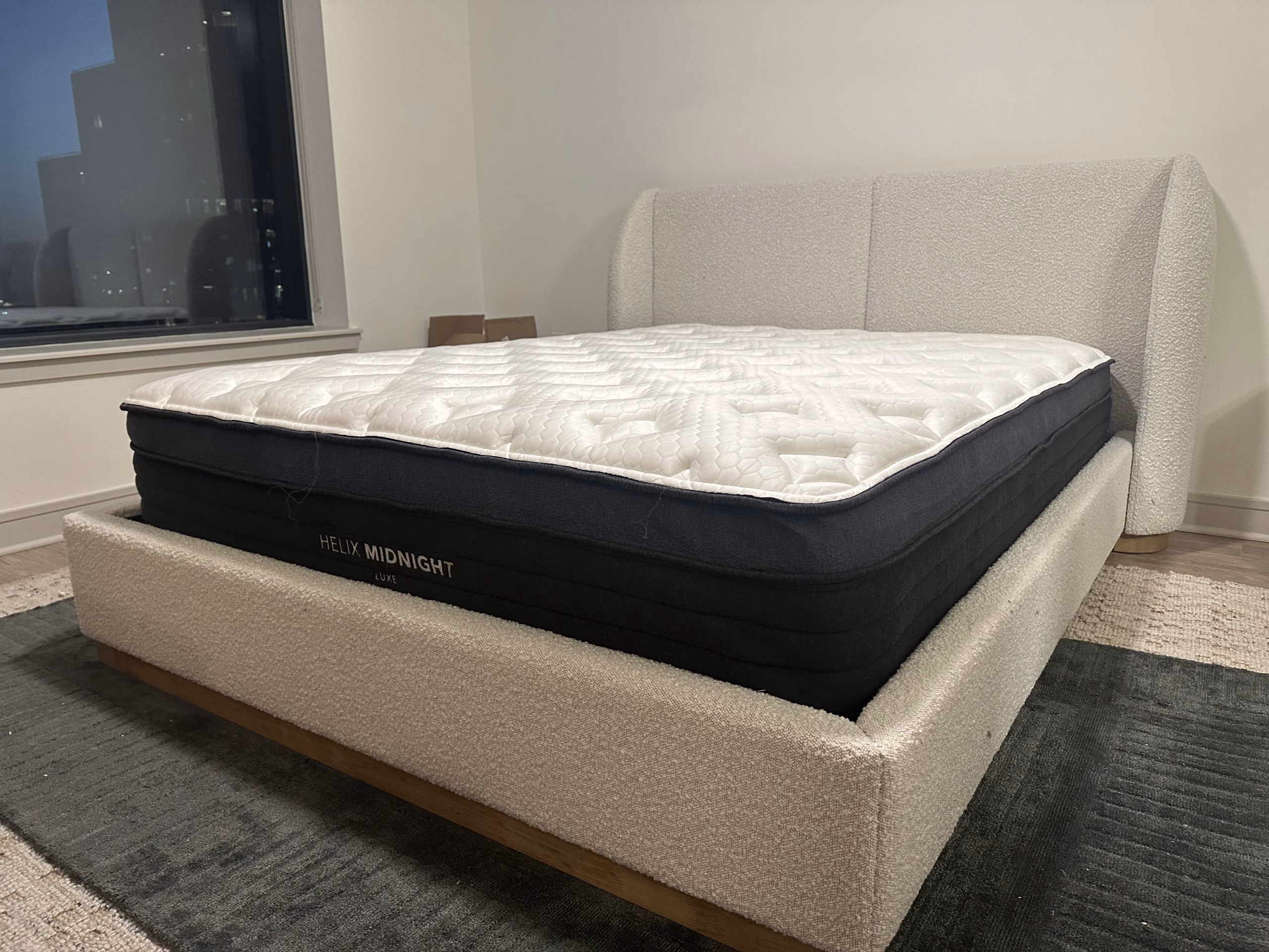A boucle-upholstered bed frame assembled in a downtown apartment.