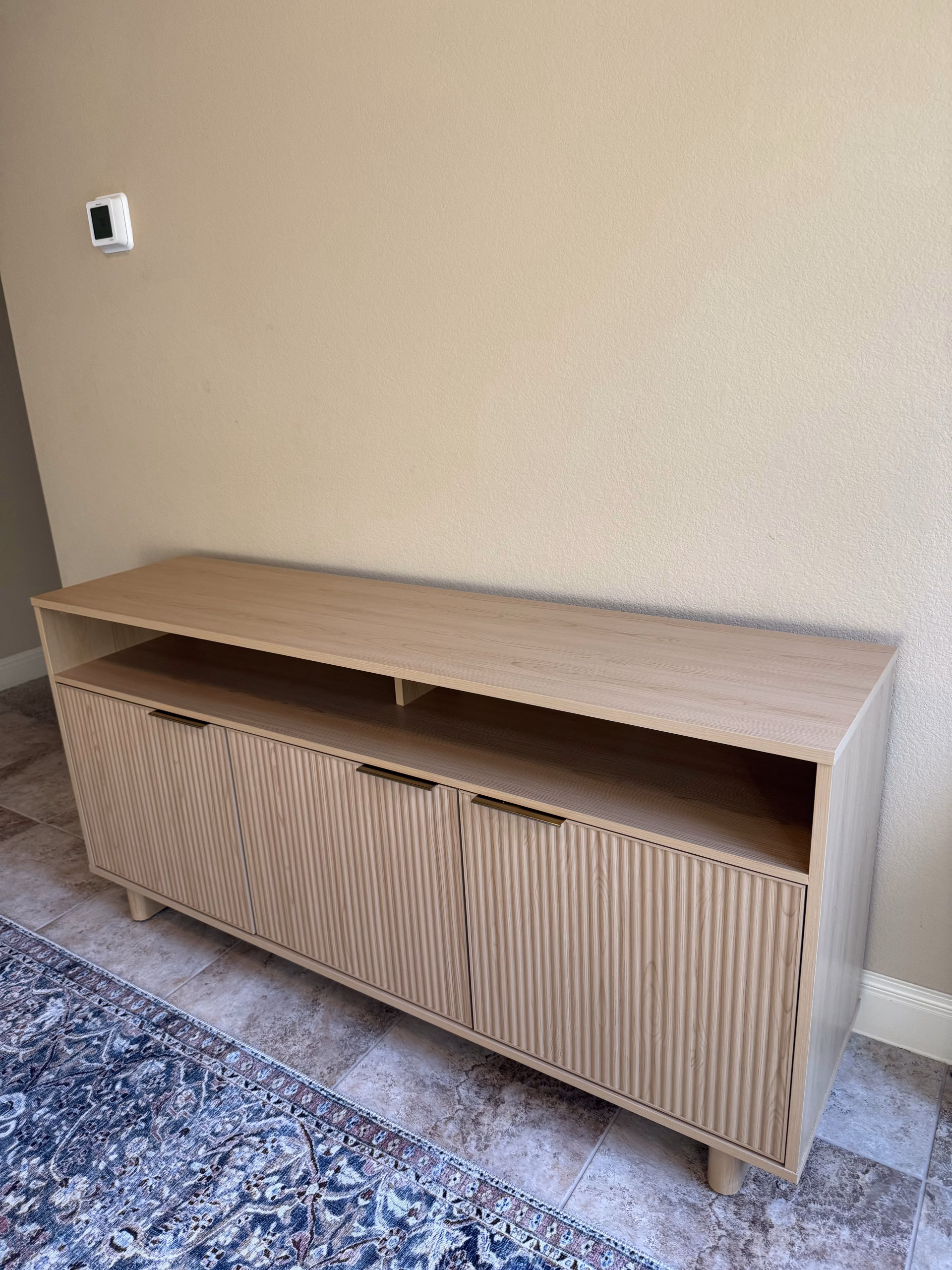 A fluted three-door media console with an open display shelf.