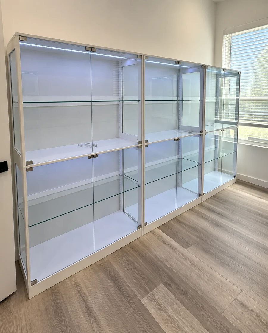 A glass display cabinet with lit shelves, assembled against a wall.